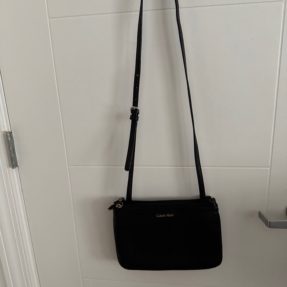 Calvin Klein long crossover shoulder handbag with 3 sections for storage.